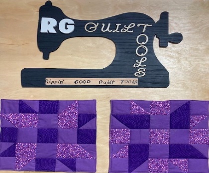 The Rippin' Good Quilt Tools sign, a black sewing machine silhouette, above two purple quilt blocks