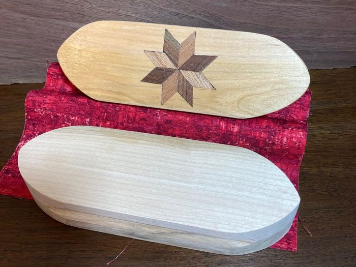 Two clappers on red fabric, one plain and one with a walnut star inlay