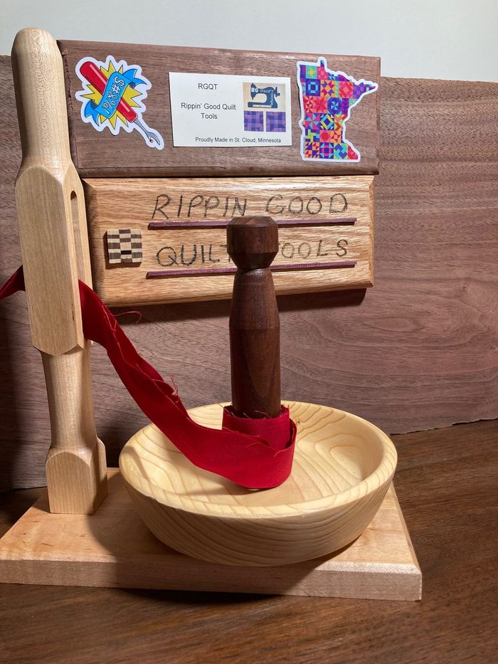A finished binding bowl with its stand, a strip of red binding wound around the spindle