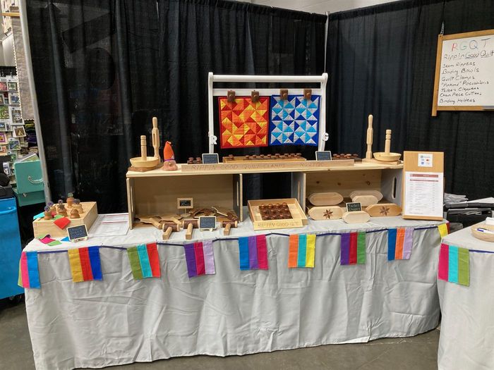 The Rippin' Good booth at a quilt show, with quilt clamps, seam mallets and clappers